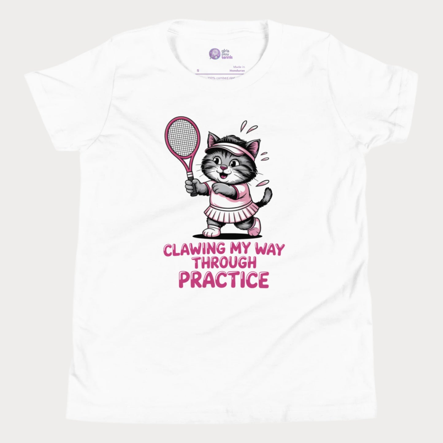 A white girls’ tennis t-shirt featuring a determined gray kitten in a pink tennis outfit holding a pink tennis racket. The kitten is sweating and focused, with the phrase “Clawing My Way Through Practice” in bold pink lettering underneath.