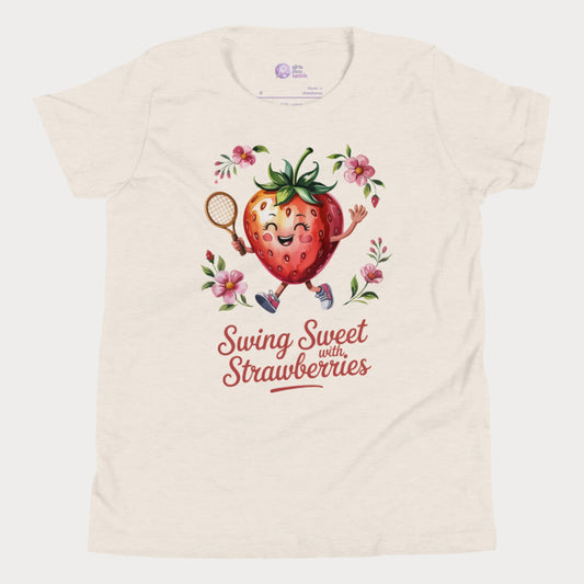 Beige girls tennis t-shirt with a smiling strawberry holding a tennis racket surrounded by pink flowers and the phrase ‘Swing Sweet with Strawberries’
