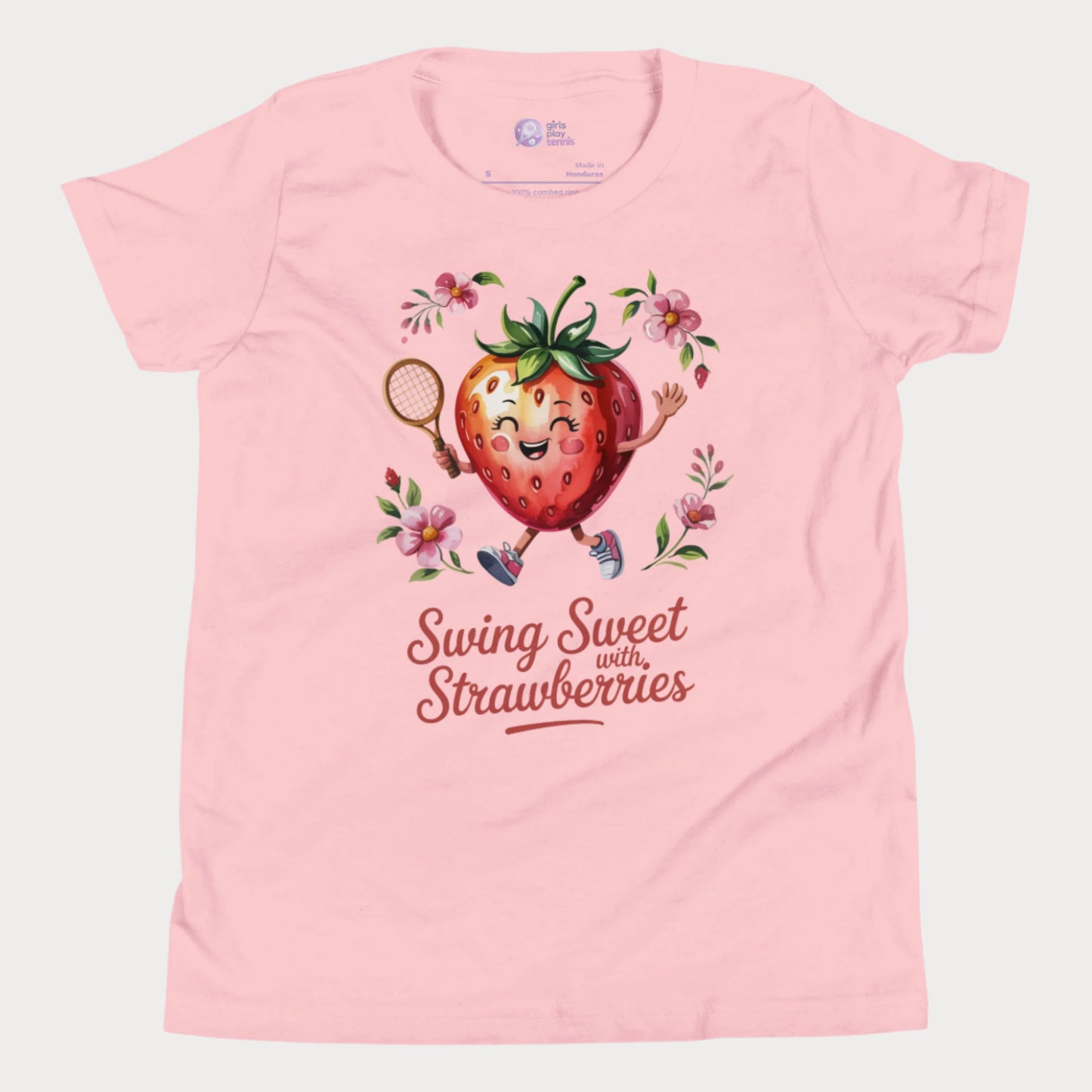 Pink girls tennis t-shirt with a smiling strawberry holding a tennis racket surrounded by pink flowers and the phrase ‘Swing Sweet with Strawberries’