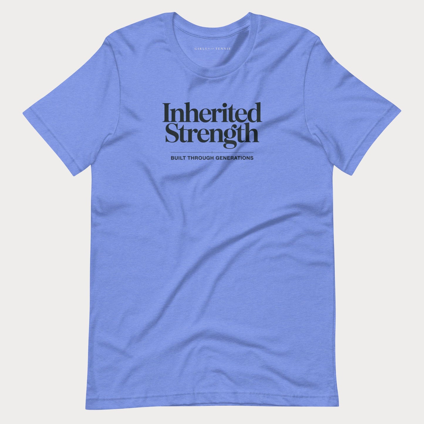 A light blue crewneck t-shirt with 'Inherited Strength' printed in black serif font on the chest, accompanied by the smaller text 'BUILT THROUGH GENERATIONS' underneath, displayed on a light gray background.