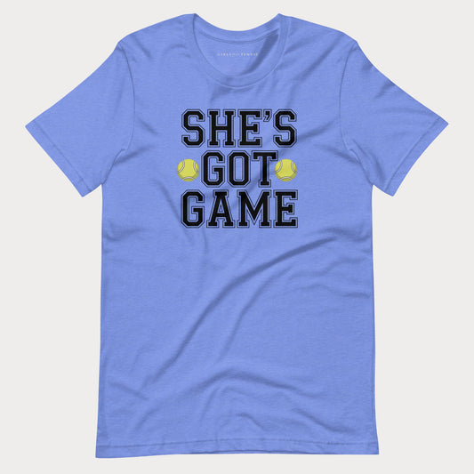 A heather blue short-sleeve women's tennis t-shirt with a graphic on the front that reads 'SHE'S GOT GAME' in black varsity-style letters, accented by two yellow tennis balls, shown on a light gray background.