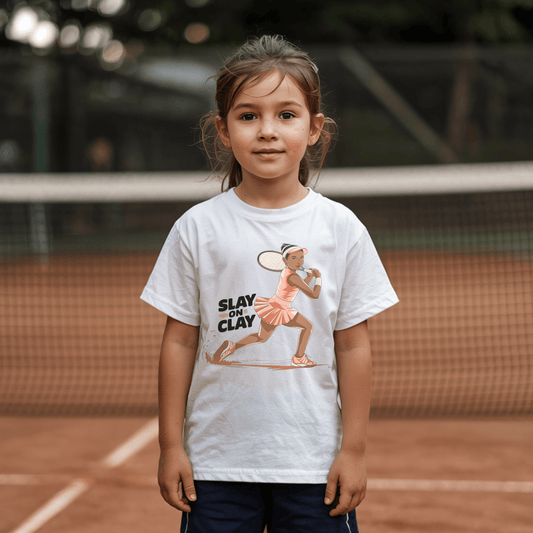 Young girl wearing a white t-shirt with a "Slay on Clay" slogan, featuring an illustrated girl in an action backend swing.