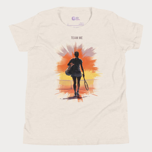 Beige girls tennis t-shirt with a silhouette of a young player walking onto a sunset-lit court and the slogan "TEAM ME" above.