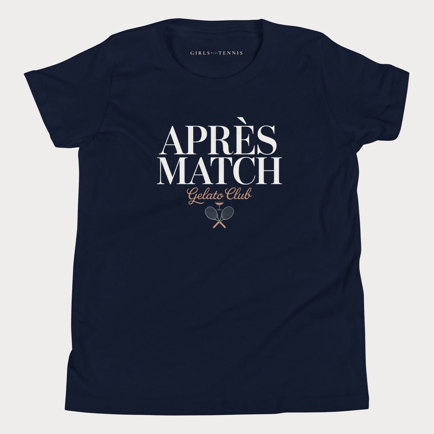 A navy blue short-sleeve girls tennis t-shirt with 'APRÈS MATCH Gelato Club' printed in white and gold on the front, featuring a small crossed tennis racket graphic. The inner neck label reads 'GIRLS PLAY TENNIS'.