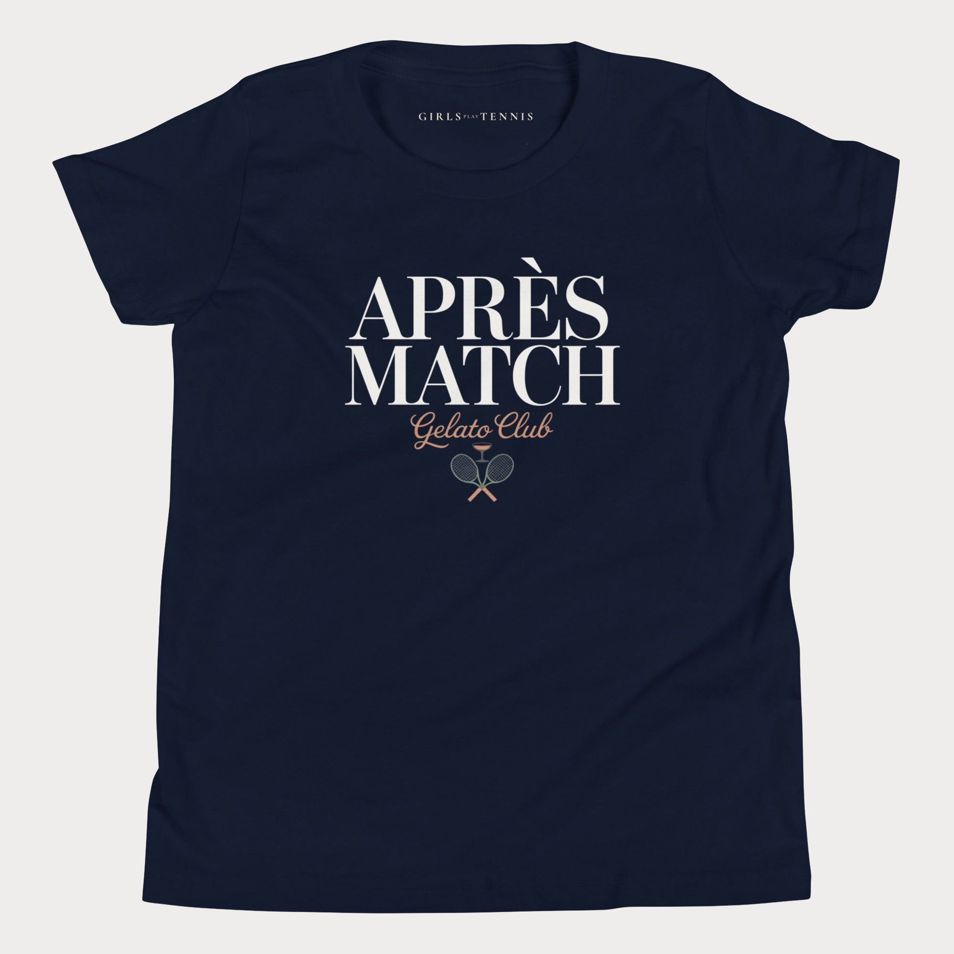 A navy blue short-sleeve girls tennis t-shirt with 'APRÈS MATCH Gelato Club' printed in white and gold on the front, featuring a small crossed tennis racket graphic. The inner neck label reads 'GIRLS PLAY TENNIS'.