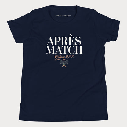 A navy blue short-sleeve girls tennis t-shirt with 'APRÈS MATCH Gelato Club' printed in white and gold on the front, featuring a small crossed tennis racket graphic. The inner neck label reads 'GIRLS PLAY TENNIS'.
