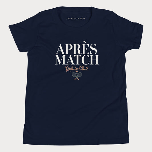 A navy blue short-sleeve girls tennis t-shirt with 'APRÈS MATCH Gelato Club' printed in white and gold on the front, featuring a small crossed tennis racket graphic. The inner neck label reads 'GIRLS PLAY TENNIS'.