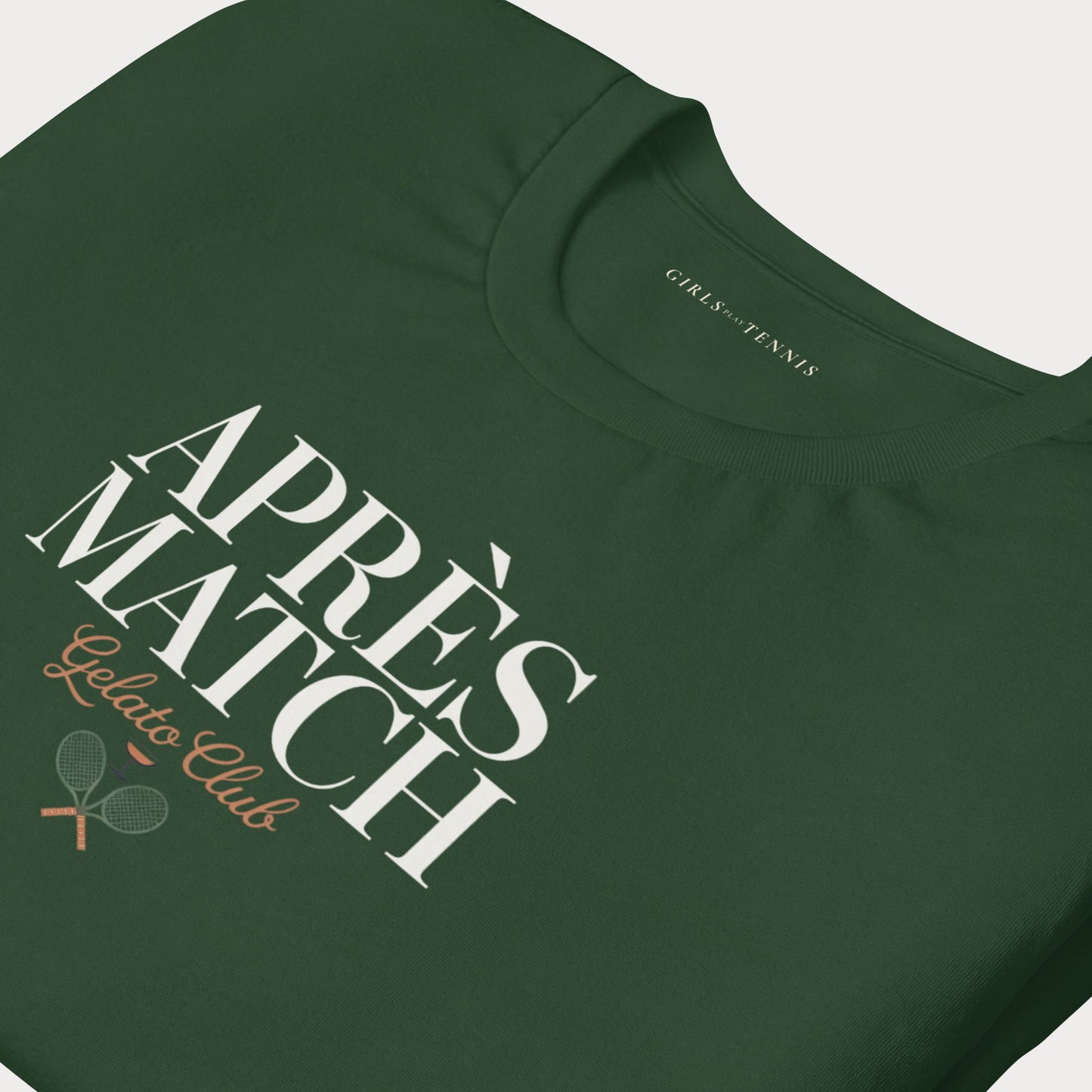 A close-up of a dark green t-shirt featuring a graphic print that reads 'APRÈS MATCH Gelato Club' with two crossed tennis rackets, on a light gray background.