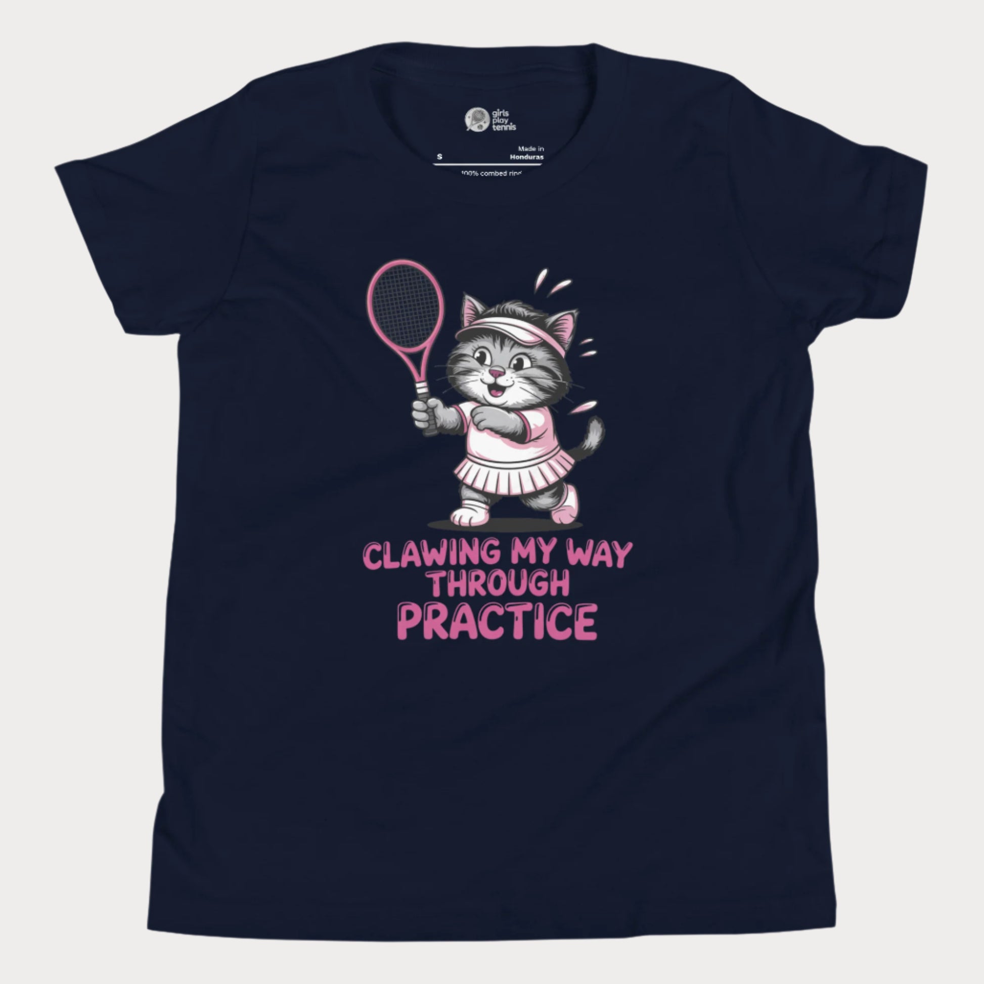 A navy girls’ tennis t-shirt featuring a determined gray kitten in a pink tennis outfit holding a pink tennis racket. The kitten is sweating and focused, with the phrase “Clawing My Way Through Practice” in bold pink lettering underneath. 