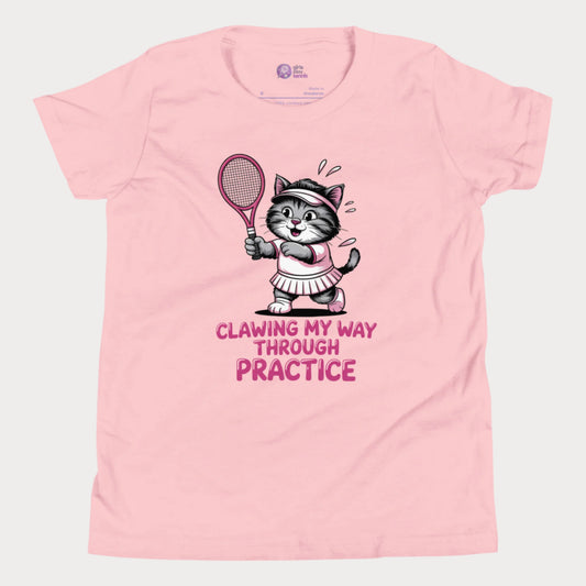 A pink girls’ tennis t-shirt featuring a determined gray kitten in a pink tennis outfit holding a pink tennis racket. The kitten is sweating and focused, with the phrase “Clawing My Way Through Practice” in bold pink lettering underneath.