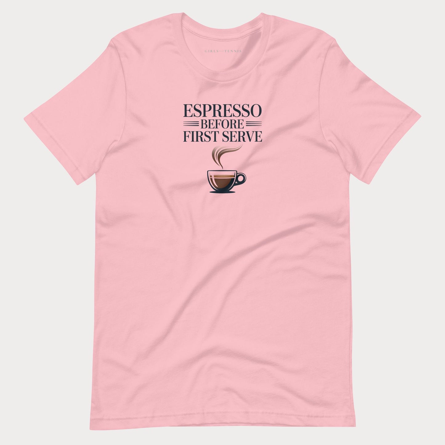 A light pink short-sleeve crewneck tennis lifestyle t-shirt featuring a graphic print on the chest that reads 'ESPRESSO BEFORE FIRST SERVE' above an illustration of a coffee cup with steam.
