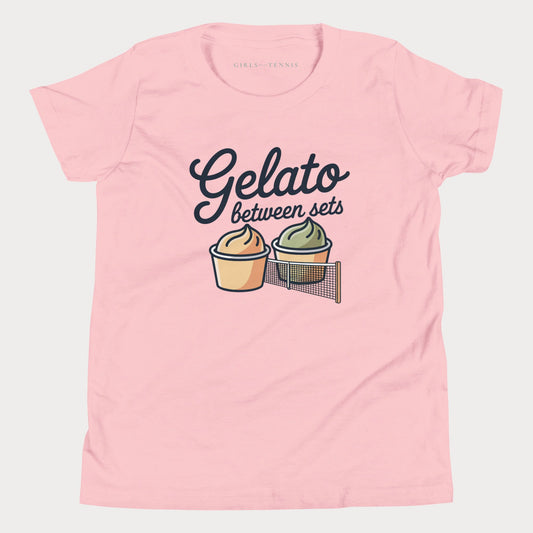 A light pink short-sleeve t-shirt with a graphic print that reads 'Gelato between sets' above two illustrated gelato cups, shown on a light gray background.