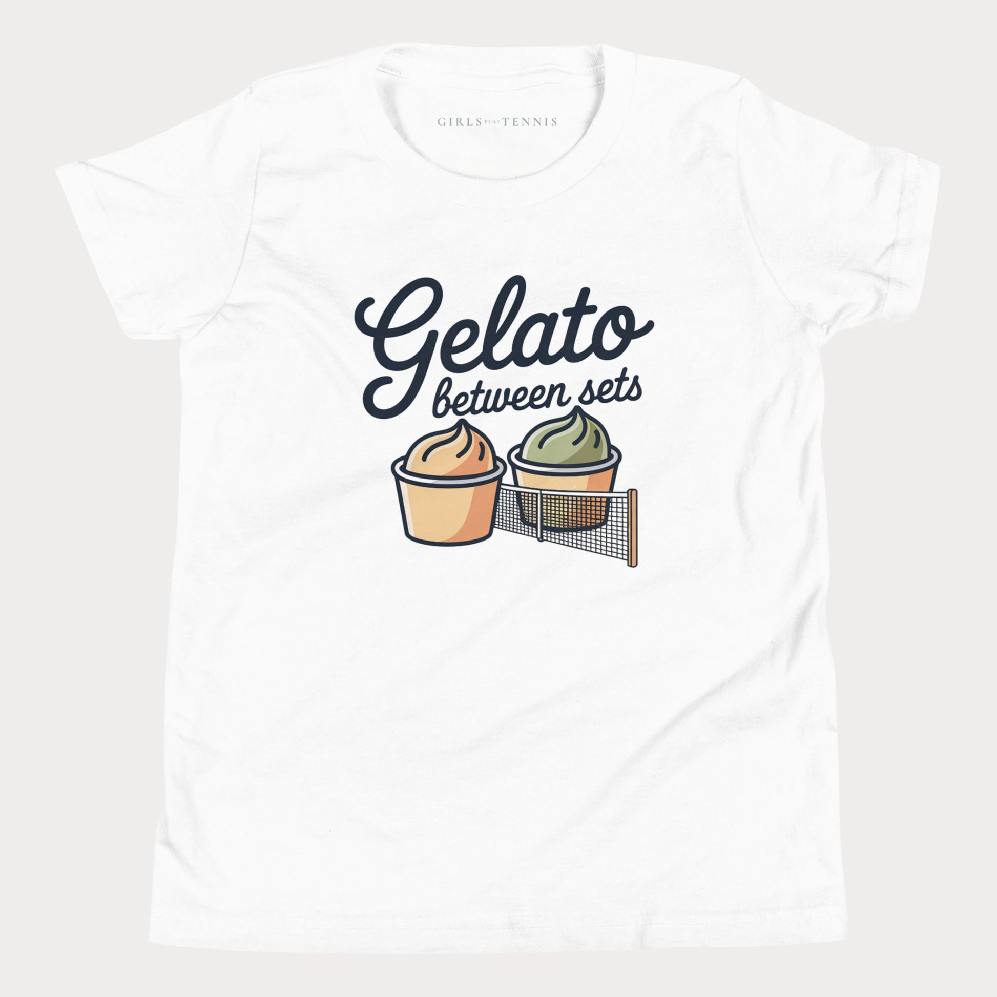 A white short-sleeve crewneck t-shirt featuring a graphic print that reads 'Gelato between sets' above two illustrated gelato cups separated by a tennis net. The inner collar shows the brand name 'GIRLS PLAY TENNIS'.
