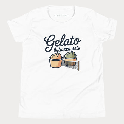 A white short-sleeve crewneck t-shirt featuring a graphic print that reads 'Gelato between sets' above two illustrated gelato cups separated by a tennis net. The inner collar shows the brand name 'GIRLS PLAY TENNIS'.