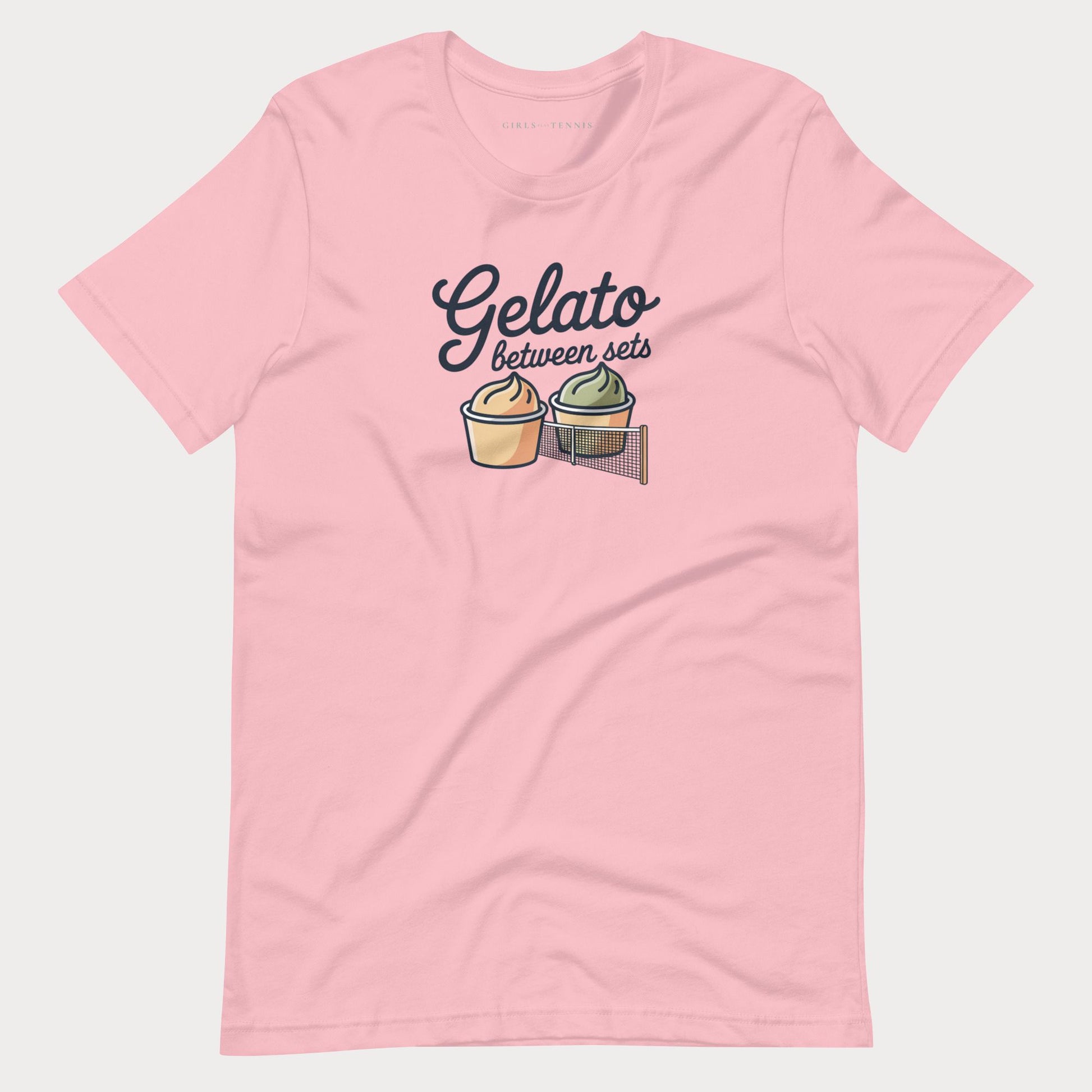 A light pink short-sleeve women's tennis t-shirt with a graphic on the chest that reads 'Gelato between sets' above two illustrated gelato cones, shown on a light gray background.