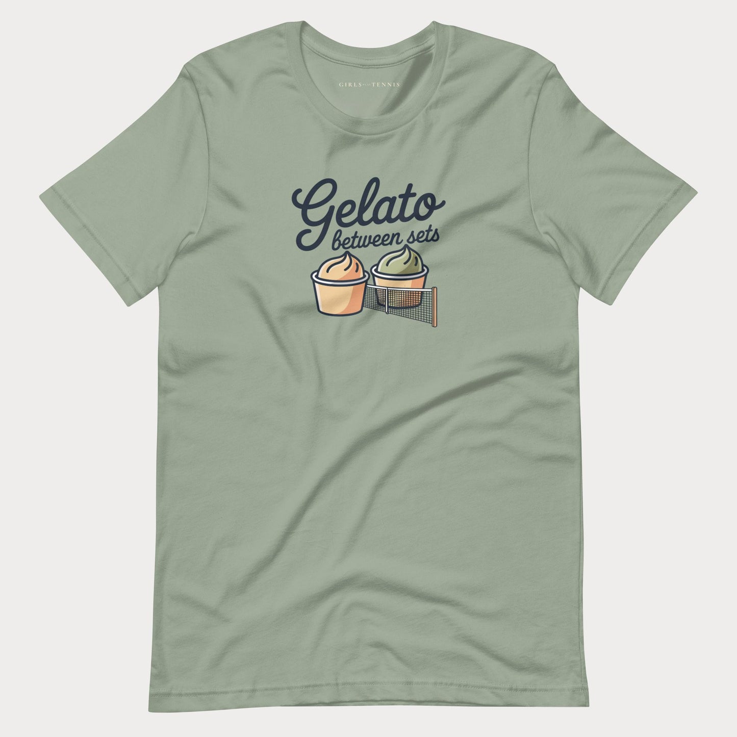 A sage green short-sleeve women's tennis t-shirt with a graphic on the chest that reads 'Gelato between sets' above two illustrated dessert cups on a tennis net.
