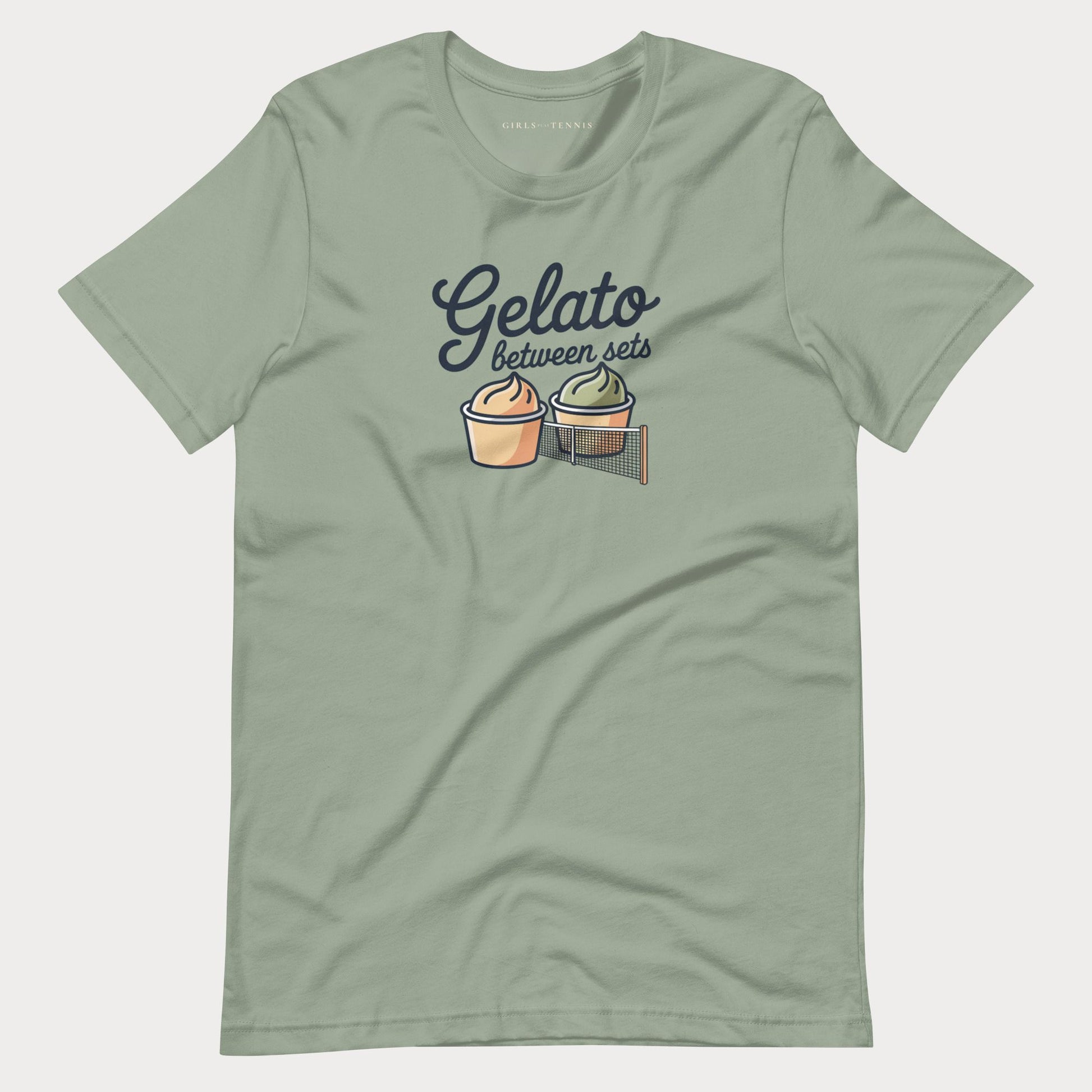 A sage green short-sleeve women's tennis t-shirt with a graphic on the chest that reads 'Gelato between sets' above two illustrated dessert cups on a tennis net.