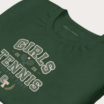 A close-up of a dark green short-sleeve t-shirt featuring a vintage-style collegiate graphic that reads 'GIRLS TENNIS' in cream and white, with crossed tennis rackets, the number '26', and 'ATHLETIC DEPT.' printed on the front.