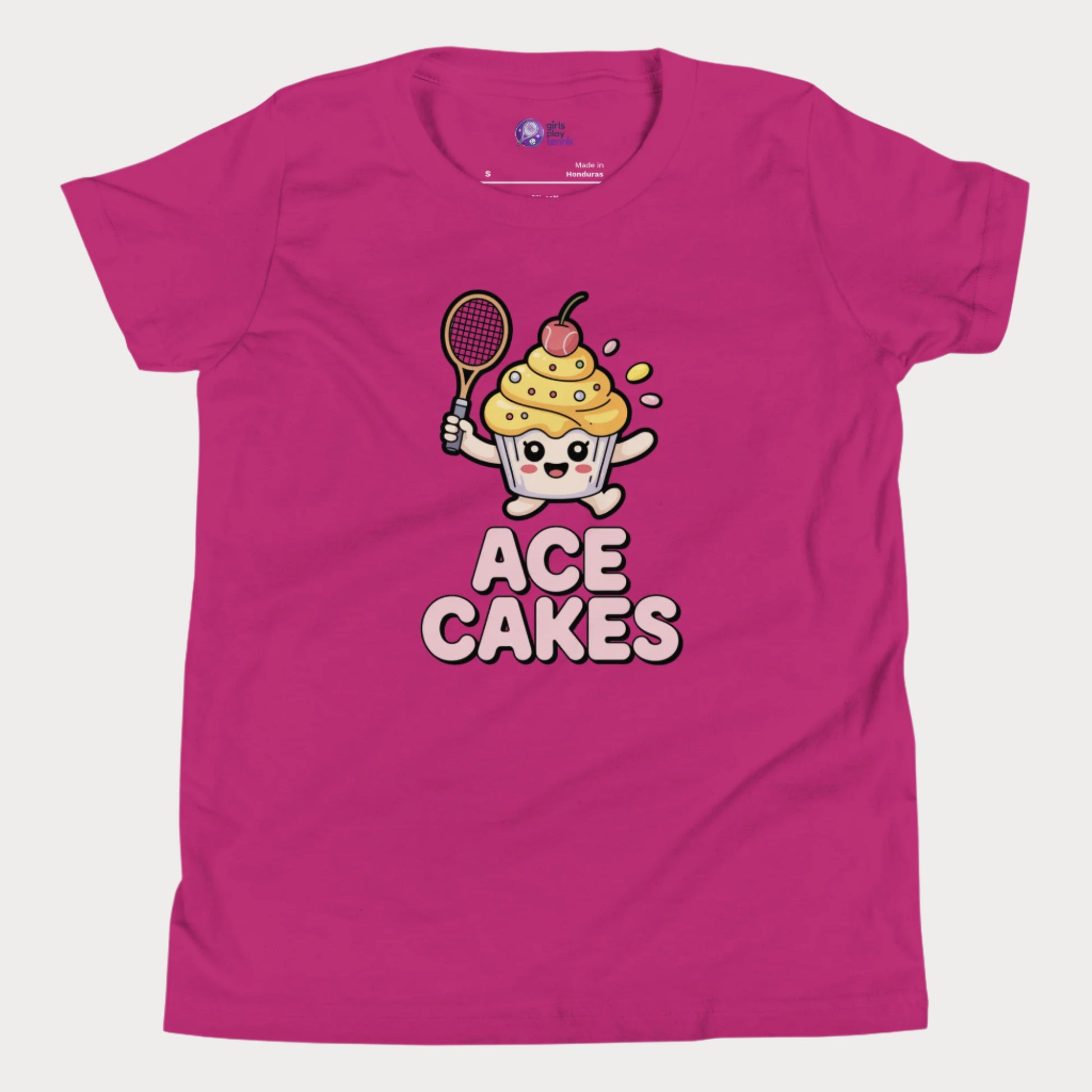 Pink girls tennis t-shirt with a cartoon cake character holding a tennis racket and the text 'ACE CAKES' on a white background.