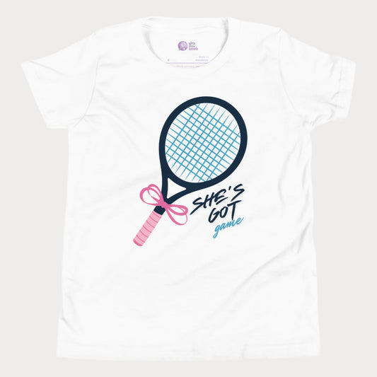 Cute white girls' tennis t-shirt featuring a stylish tennis racket with a pink bow and the phrase "She's Got Game" in bold lettering.