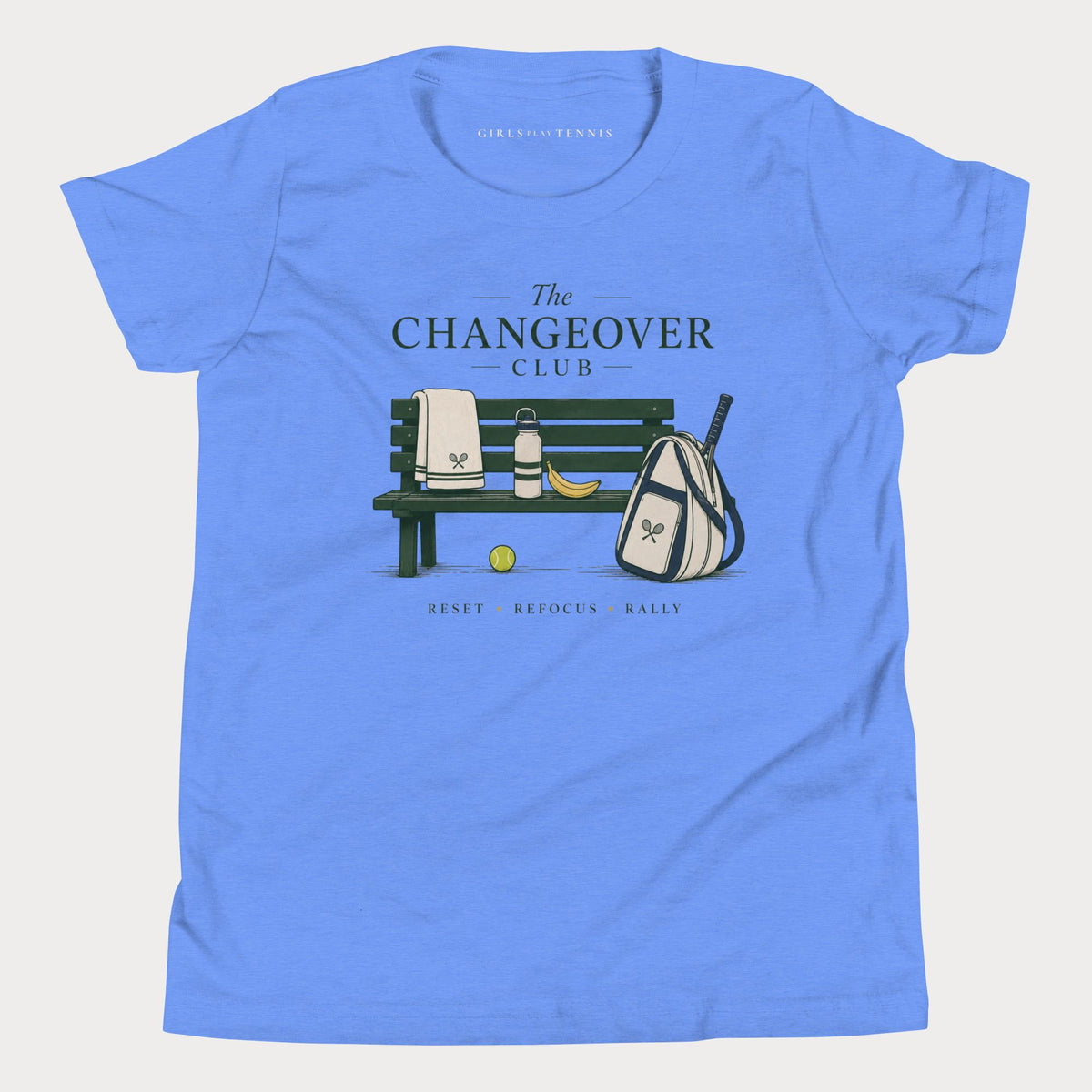 Blue The Changeover Club girls' tennis T-shirt with a courtside bench, towel, racket bag and banana illustration
