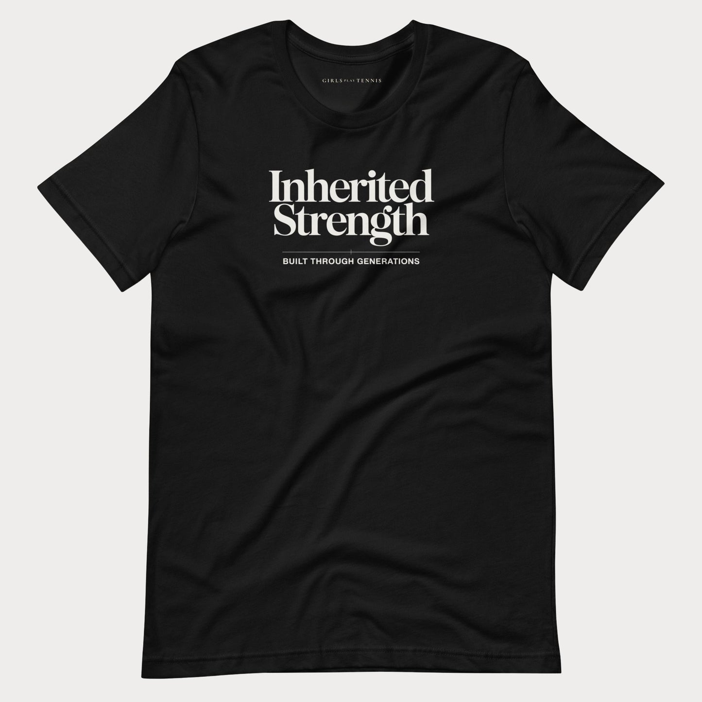 A black short-sleeve crewneck women's tennis t-shirt with white printed text reading 'Inherited Strength' and 'BUILT THROUGH GENERATIONS' on the chest, displayed flat against a light gray background.