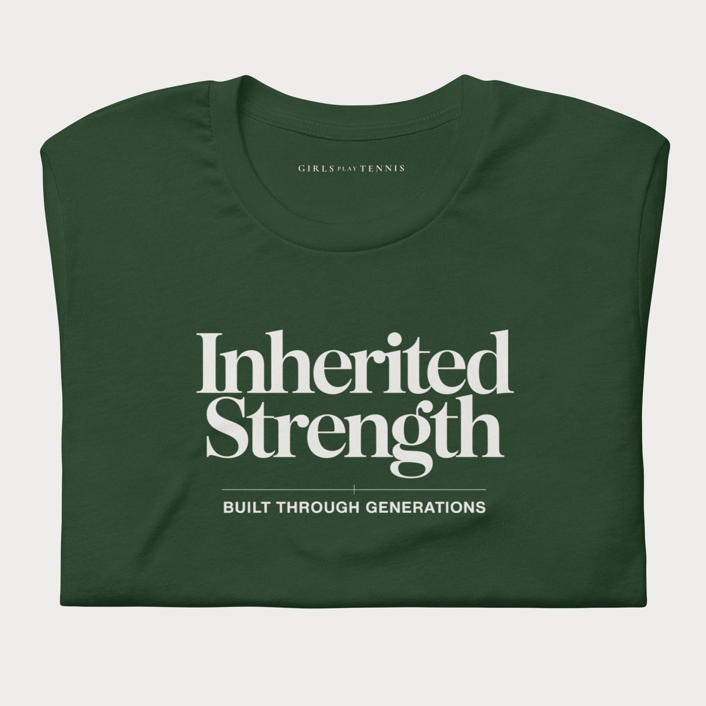 A dark green folded short-sleeve women's tennis t-shirt with white text reading 'Inherited Strength' and 'BUILT THROUGH GENERATIONS' on the front, shown on a light gray background.