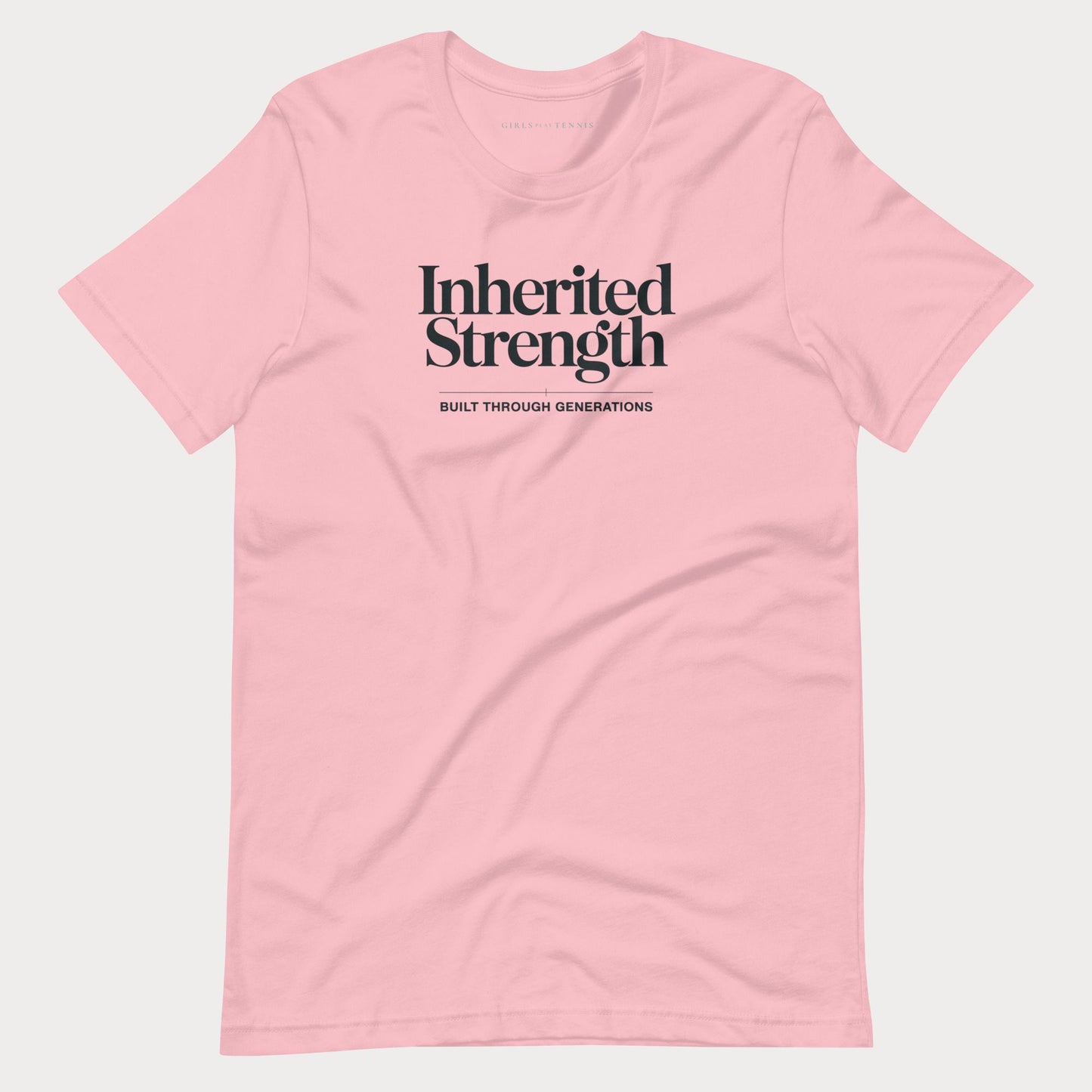 A light pink short-sleeve crewneck t-shirt with black text on the chest reading 'Inherited Strength' and 'BUILT THROUGH GENERATIONS' underneath, displayed on a light gray background.