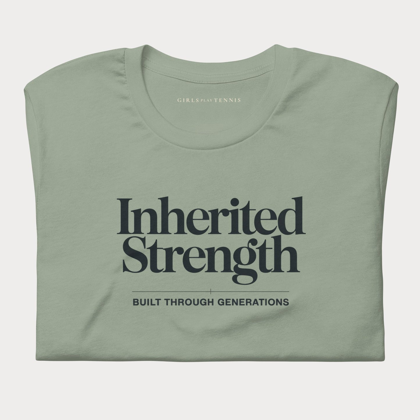A folded sage green t-shirt with dark navy text reading 'Inherited Strength' and 'BUILT THROUGH GENERATIONS' on the front, displayed against a light gray background.