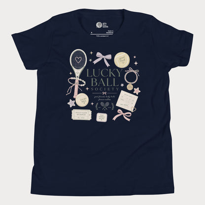 Navy girls tennis tee featuring lucky ball society artwork with bows, bracelets, and vintage tennis lifestyle details