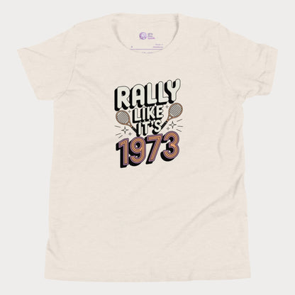 Beige girls tennis t-shirt with retro slogan ‘Rally Like It’s 1973’ and crossed tennis rackets