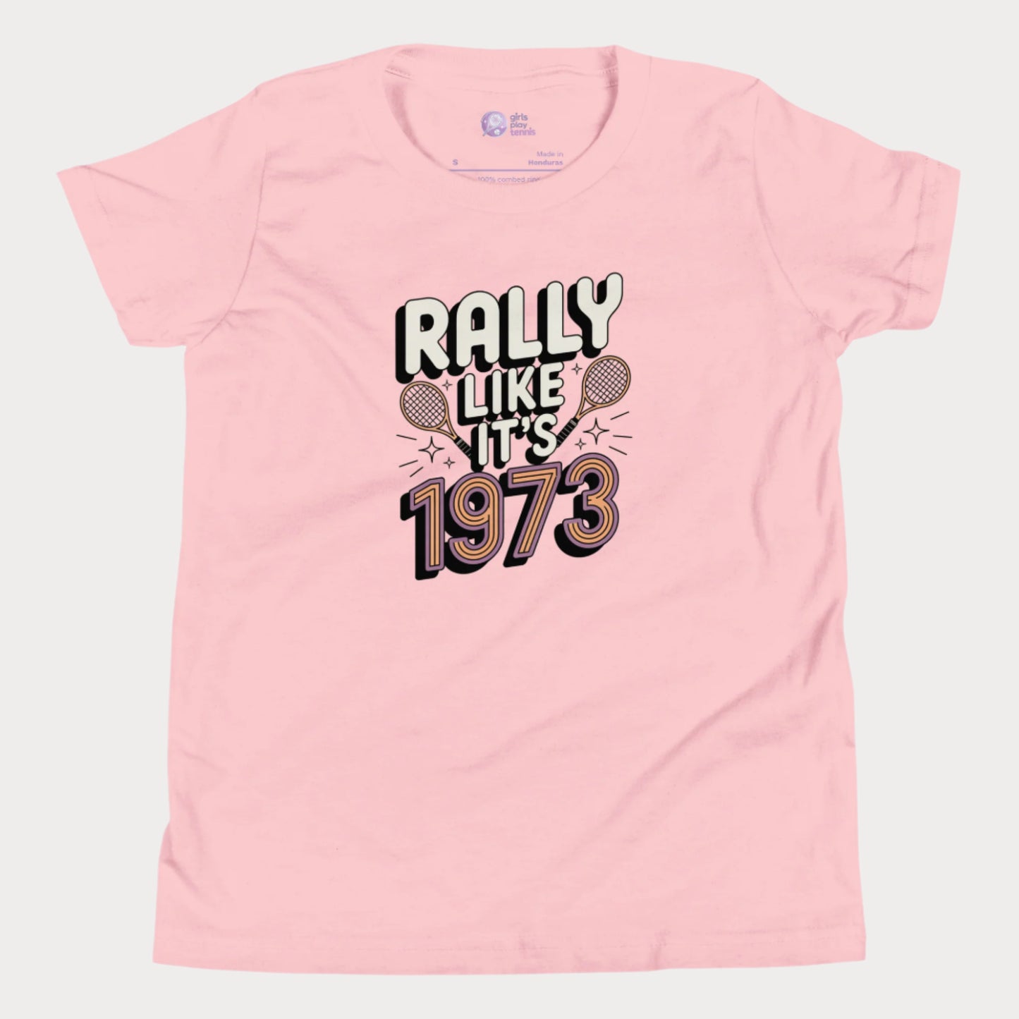 Pink girls tennis t-shirt with retro slogan ‘Rally Like It’s 1973’ and crossed tennis rackets.