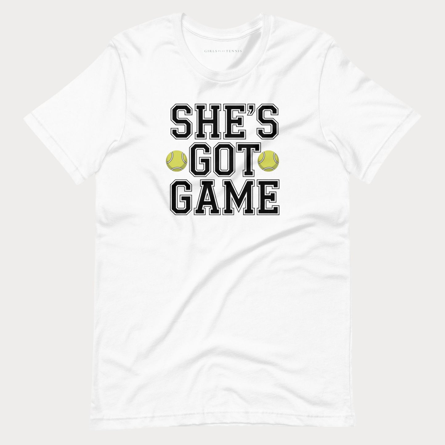 A white short-sleeve crewneck women's tennis t-shirt featuring the text 'SHE'S GOT GAME' in a black varsity-style font with a white outline, accented by two yellow-green tennis balls between the words 'GOT' and 'GAME'.
