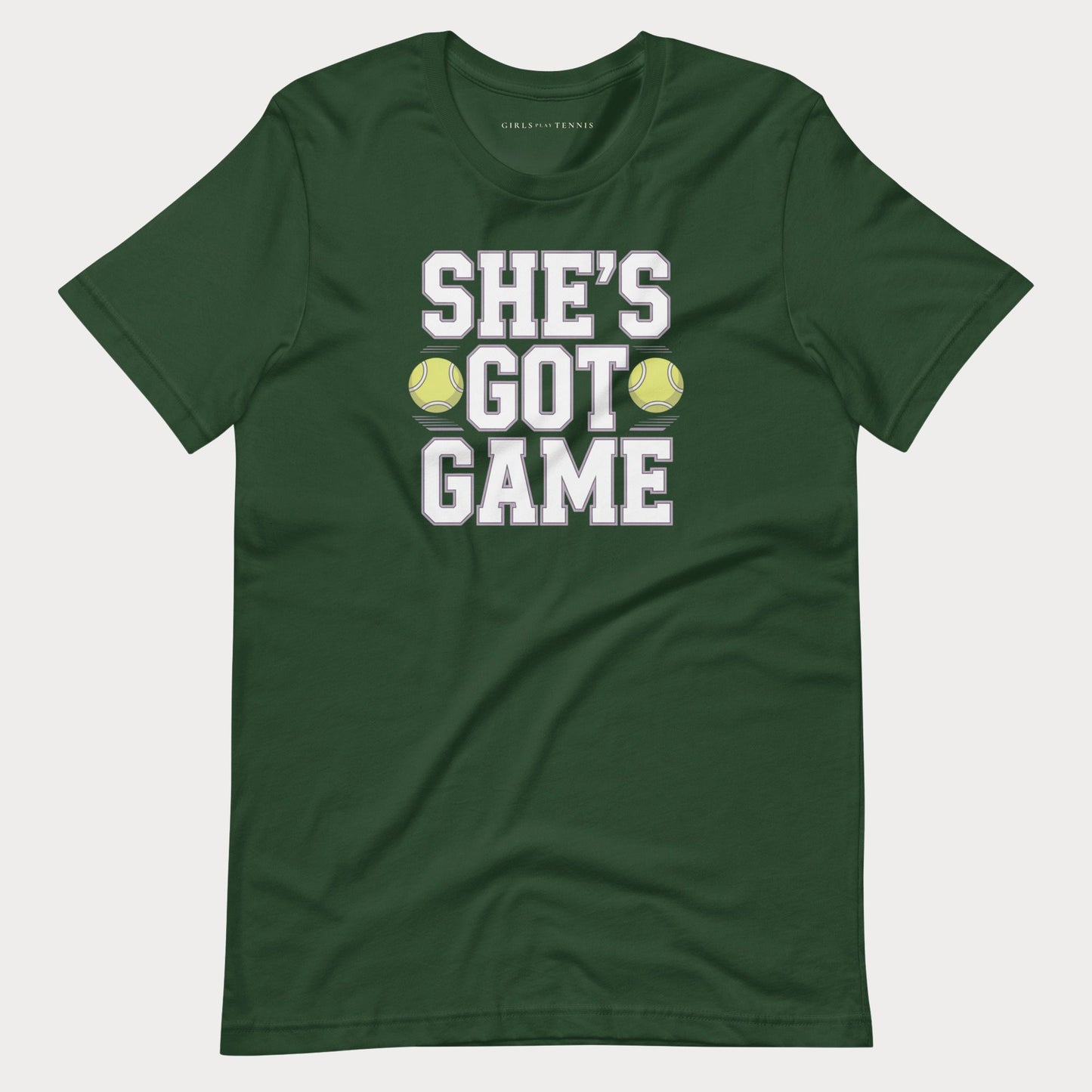 A dark green short-sleeve women's tennis t-shirt with a graphic print on the front that reads 'SHE'S GOT GAME' in white block letters, with two yellow tennis balls replacing the 'O' in 'GOT'.