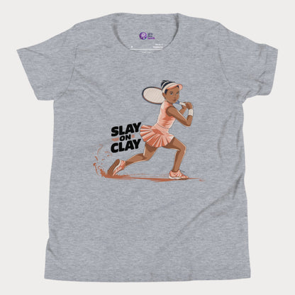 Grey heather tennis T-shirt featuring an illustrated young girl in a fierce backhand stance, sliding on a clay court with the phrase "Slay on Clay."