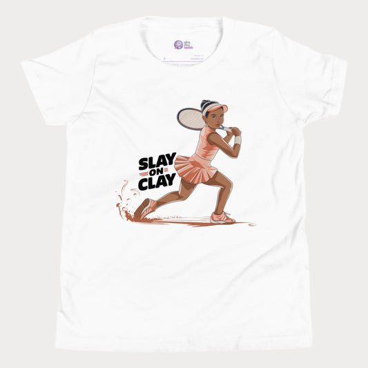 White tennis T-shirt featuring an illustrated young girl in a fierce backhand stance, sliding on a clay court with the phrase "Slay on Clay."