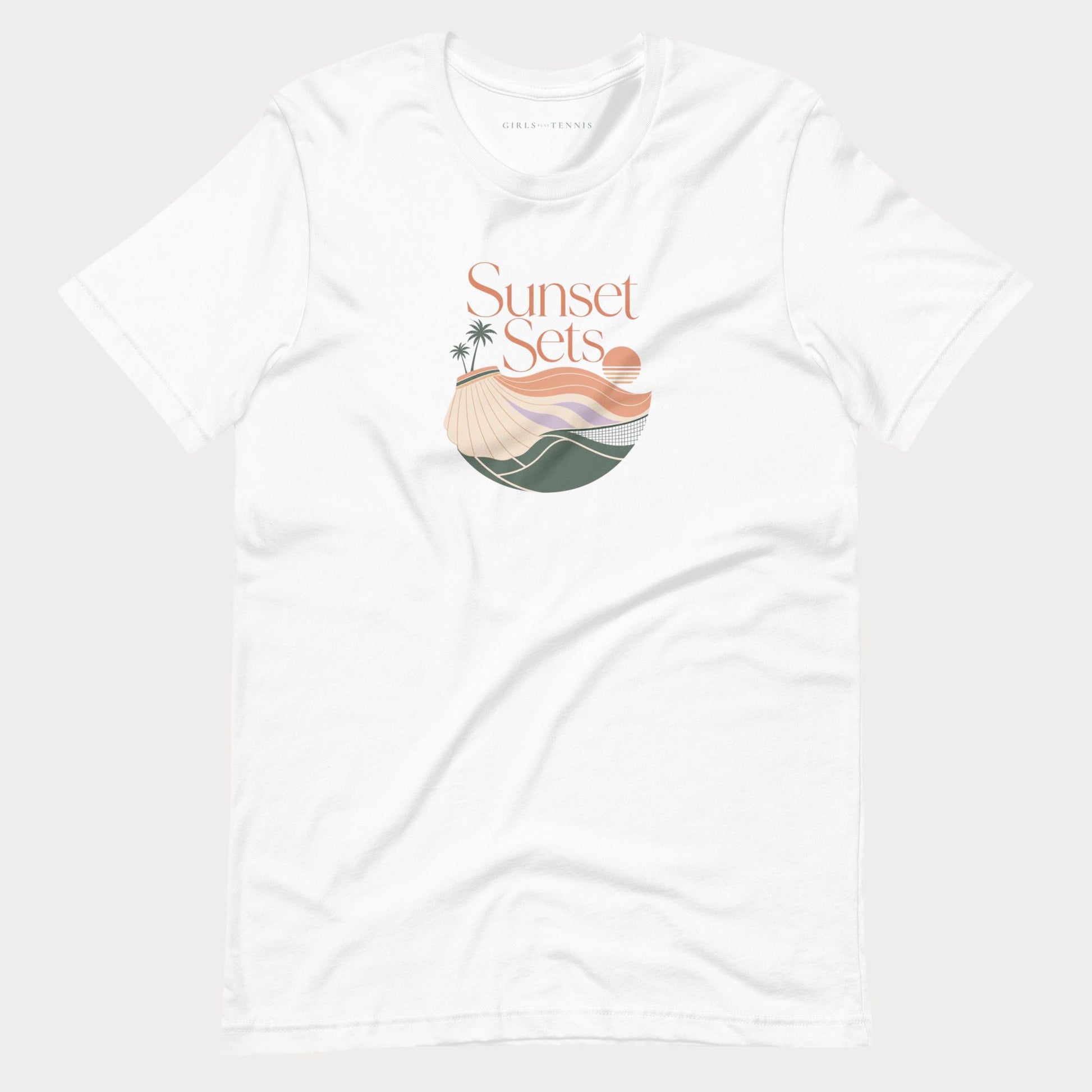 A white short-sleeve crewneck women's lifestyle tennis t-shirt featuring a 'Sunset Sets' graphic on the chest with a beach, palm trees, and waves in muted orange, beige, and green tones, displayed on a light gray background.