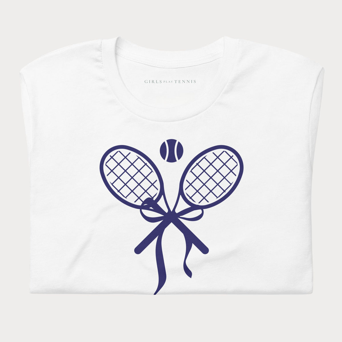 Folded white women's tennis t-shirt showing a navy crossed tennis racket bow graphic with a tennis ball above
