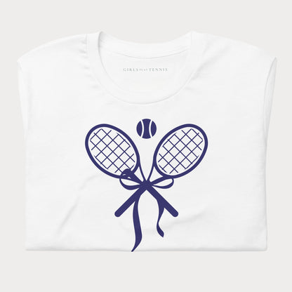 Folded white women's tennis t-shirt showing a navy crossed tennis racket bow graphic with a tennis ball above
