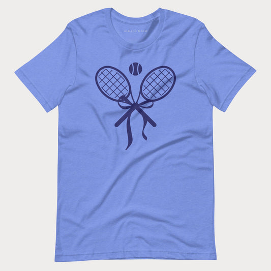 A heathered periwinkle blue short-sleeve tennis t-shirt with a dark navy graphic of two crossed tennis rackets, a tennis ball, and a ribbon on the chest, displayed flat against a light gray background.