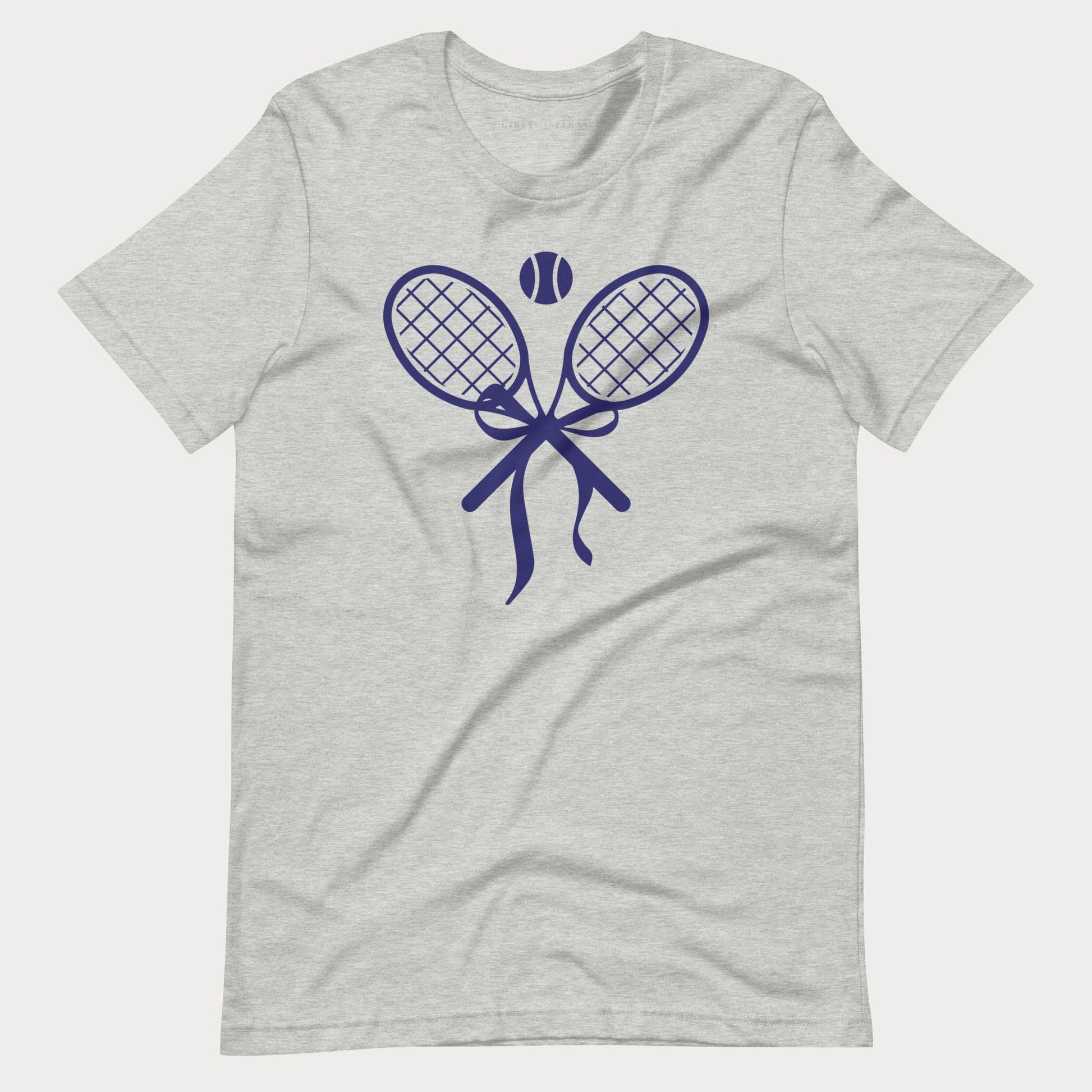 A light heather gray short-sleeve tennis t-shirt with a navy blue graphic of two crossed tennis rackets, a tennis ball, and a ribbon bow on the chest, displayed against a light gray background.