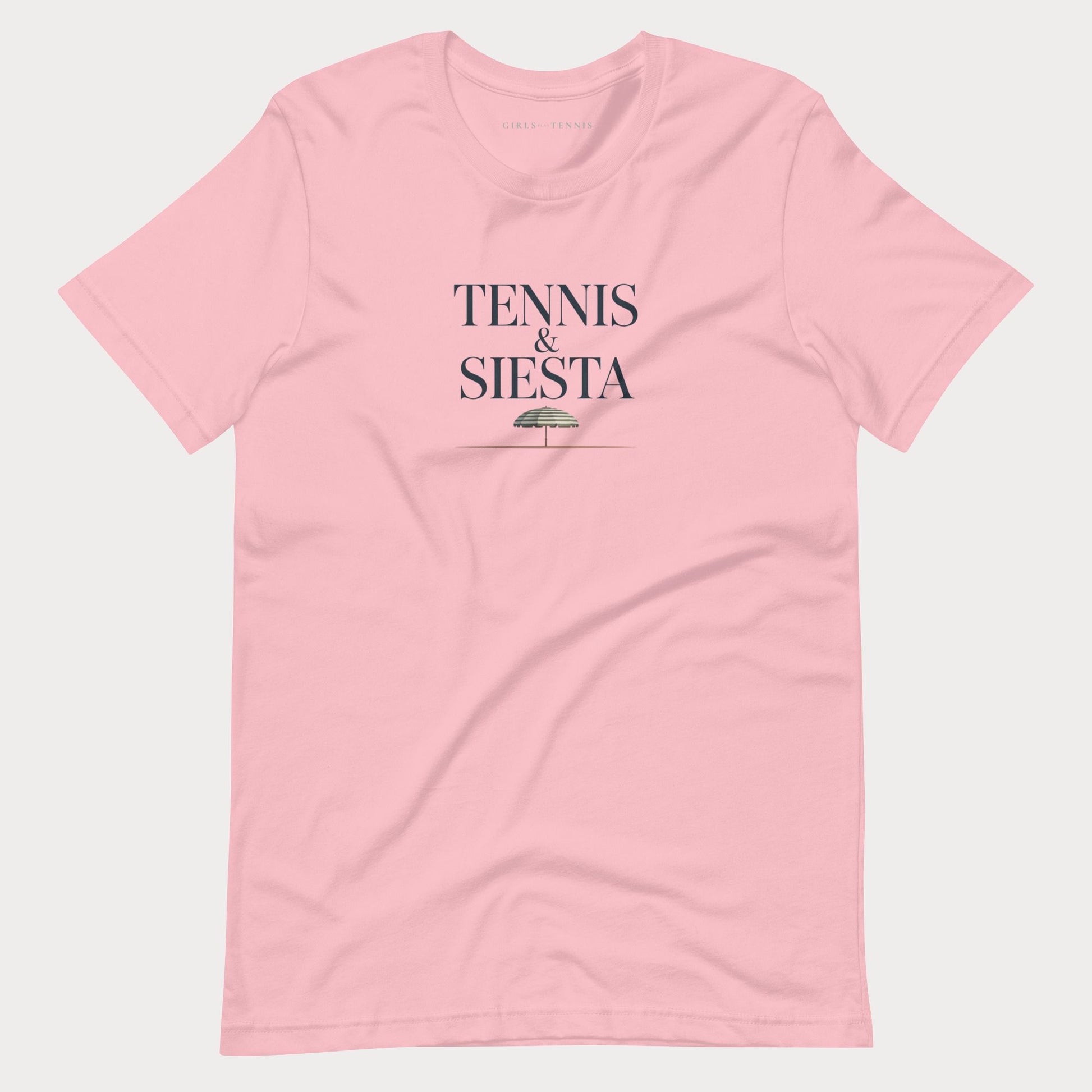 A light pink short-sleeve crewneck women's lifestyle t-shirt with 'TENNIS & SIESTA' printed in dark navy text on the chest, accompanied by a small green umbrella graphic, displayed on a light gray background.
