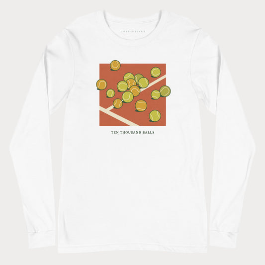 White Ten Thousand Balls women's tennis long-sleeve T-shirt with a clay-red square covered in scattered tennis balls above the words Ten Thousand Balls