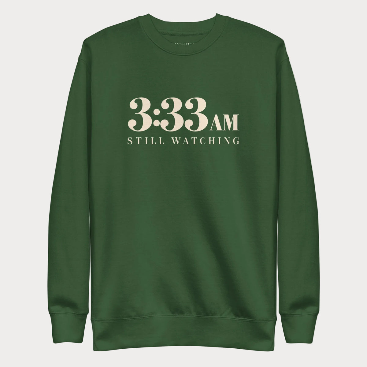 Forest green 3:33 AM women's tennis crewneck sweatshirt with cream lettering reading 3:33 AM above Still Watching