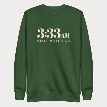 Forest green 3:33 AM women's tennis crewneck sweatshirt with cream lettering reading 3:33 AM above Still Watching