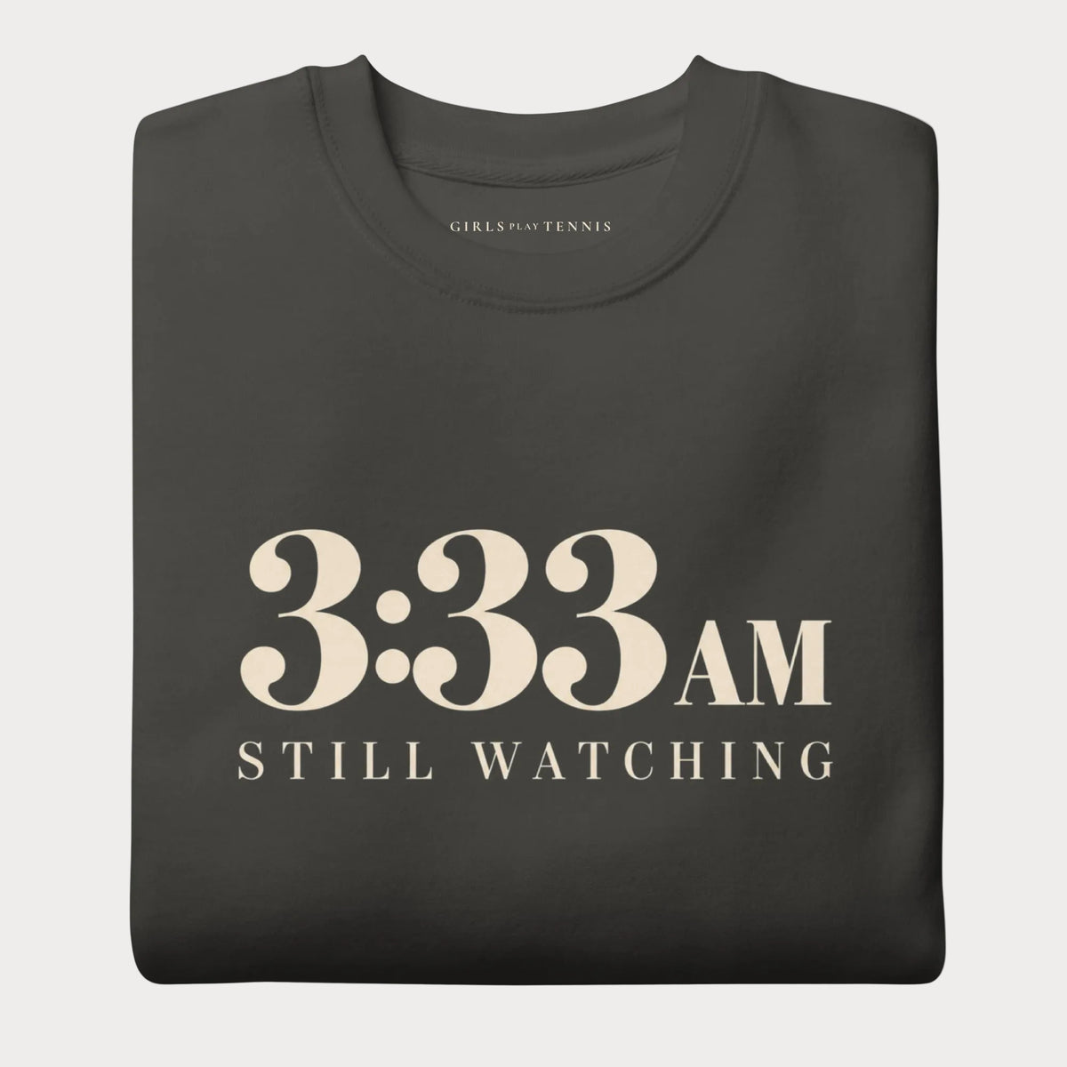 Folded vintage black 3:33 AM women's tennis crewneck sweatshirt with cream lettering reading 3:33 AM above Still Watching