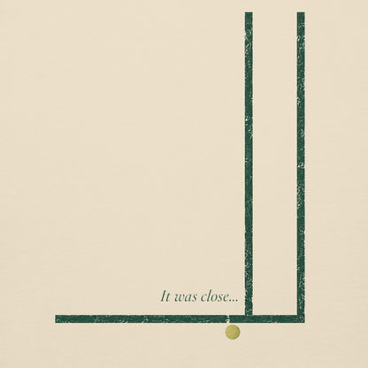 Close-up of the worn forest green court-corner lines, a tennis ball just past the line and the script caption It was close... on a bone It Was Close... crewneck sweatshirt
