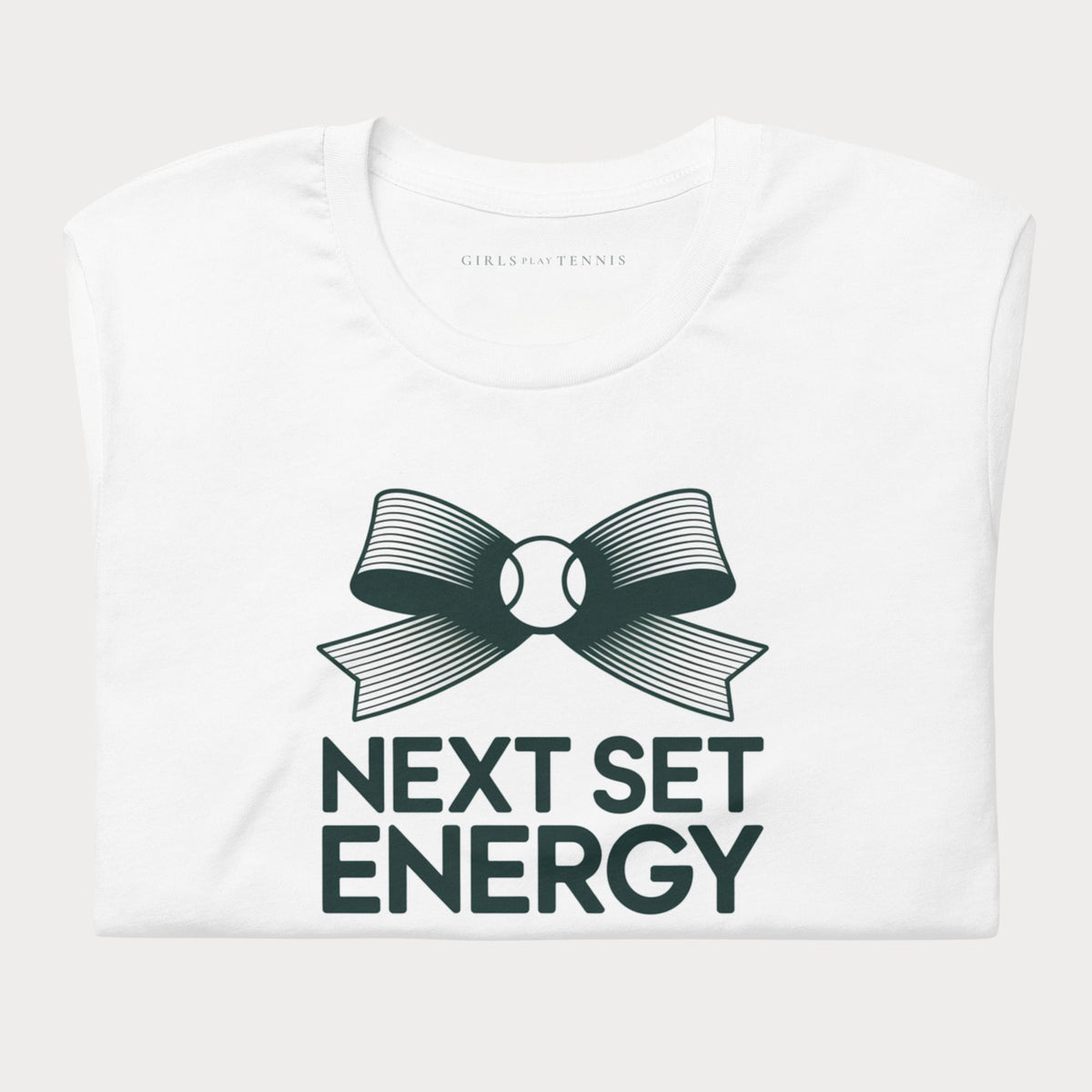 Folded white Next Set Energy women's tennis T-shirt with a bow around a tennis ball above bold lettering